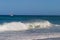 A catamaran off the coast of Kauai with a big wave in the foreground