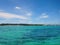 Catamaran, sailboat parked in the ocean by the shore, covered with palm trees and tropical plants, against the blue sky