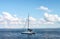 Catamaran yacht on ocean with mountains on shore on horizon under blue sky with clouds