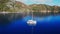 Catamaran yacht at sea surrounded by mountains and forest.