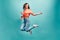 Catch fun emotions! Young beautiful woman who is dressed in an orange shirt and blue jeans bouncing on a blue background with