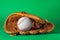 Catcher\\\'s mitt and baseball ball on green background. Sports game