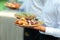 Catering - food, plate and hand. Waiters carrying plates with sweets, croissants and fruits