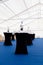 Catering, high buffet tables with a black and white tablecloth in lobby, large tent with blue floor. Concept banquet, table