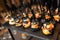 Catering in restaurant. Appetizing snacks with salmon and cheese balls in black sesame on black plate with black forks. Closeup vi