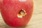 A caterpillar climbs out of a hole in a red apple