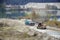 Caterpillar loader and dump truck works at the opencast mining quarry. Heavy machinery in the open pit at river. Dozer and truck