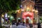 Catholic church cathedral at night. People praying, mass celebration outside the building. Neon lights. Concrete benches. Scooters