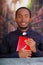 Catholic priest wearing traditional clerical collar shirt sitting and holding bible looking into camera, religion