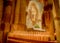 Catholic saint statue at a church shrine with lit candles and church pillars