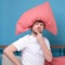 Cauacsian young man with pillow on head lying in bed and screaming being alone stressed because of quarantine