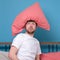 Cauacsian young man with pillow on head lying in bed and screaming being alone stressed because of quarantine