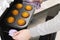 Caucasain woman holding tray with freshly made cupcakes or maffins at the kitchen