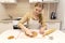 Caucasain woman rolls out the dough with a rolling pin and cuts cookies with cookie cutters at the kitchen