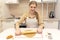 Caucasain woman rolls out the dough with a rolling pin and cuts cookies with cookie cutters at the kitchen