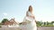 Caucasian 25-year-old beautiful blonde in a long white dress walks on a lavender field on a sunny summer evening with a