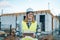 Caucasian 30s engineer woman wearing uniform and safety helmet under inspection and checking construction by tablet