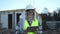 Caucasian 30s engineer woman wearing uniform and safety helmet under inspection and checking construction by tablet