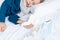 Caucasian 7 year old sick boy sleeping with handkerchief in hand and protective mask, thermometer on the bed. Virus