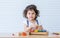 Caucasian adorable cute curly hair little girl wearing white shirt, staying alone, playing toys and doll in living room at home