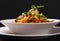 Caucasian Asian cuisine, noodle with pasta, meat, sauce and herbs in a white plate on a dark