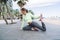 Caucasian athlete bending for stretching legs having morning workout at seashore