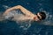 Caucasian athlete-swimmer swims in blue water. Portrait of a young male triathlete swimming in swimming goggles