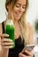 Caucasian attractive woman holding green smoothie bottle and laughing. Healthy lifestyle concept