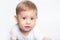 Caucasian baby boy drooling dressed in a white t-shirt on a white background closeup