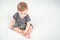 Caucasian baby boy in a khaki shorts sitting on bed in room. View from top above. Healthy childhood lifestyle