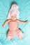 A caucasian baby wrapped in a pink towel lying on a blue sheet with his arms outstretched in different directions. View from the