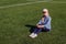 A Caucasian beautiful woman of fifty years in sunglasses sitting on artificial grass
