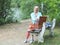 A Caucasian beautiful woman sits on a bench in the forest near the lake and opens a picnic basket