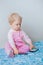 Caucasian blond baby making a call, playing with mobile cell phone with funny expression on face