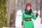 Caucasian Blond Girl in Fashionable Green Dress and Kokoshnik with Flowery Pattern and Beads. Posing in Winter Snowy Park Outdoors