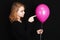 Caucasian blond girl pointing with finger pink balloon