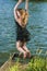 Caucasian Blond Woman in Dress Jumping Near Water Shore