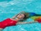 Caucasian blonde girl floats in the pool with the flag of pride