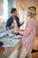 Caucasian blonde washing dishes in company of a young beardy guy