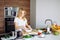 Caucasian blonde woman cooking marinade for tasty kebabs at kitchen table