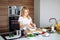 Caucasian blonde woman cooking marinade for tasty kebabs at kitchen table