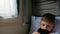 Caucasian boy 7- 9 years old uses a smartphone rides a train near the window. A child browses the Internet on a mobile device whil