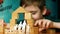 A caucasian boy of 7 years old builds a toy house from wooden cubes, the inscription family, a silhouette of a family cut out of p