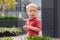 Caucasian boy child in red t-shirt standing in park outside looking in camera.