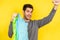 Caucasian boy holding recyclable, foldable and reusable shopping bags on a yellow background
