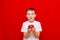 Caucasian boy kid child schoolboy holds a red Apple in his hands. Vitamins and fruits, healthy food. bright red wall