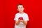 Caucasian boy kid child schoolboy holds a red Apple in his hands. Vitamins and fruits, healthy food. bright red wall