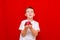 Caucasian boy kid child schoolboy holds a red Apple in his hands. Vitamins and fruits, healthy food. bright red wall