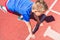 Caucasian boy,kid prepare to start running on a red track.young boy in starting position ready for running.Summer day