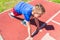 Caucasian boy,kid prepare to start running on a red track.young boy in starting position ready for running.Summer day